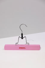 Pink wooden hanger with metal clip for organizing hair accessories in the Hair Extension Storage Bag & Hanger